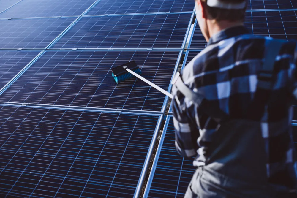 Technician cleaning a rooftop solar array with a soft brush