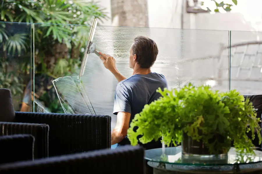 Window cleaner pulling a squeegee across residential glass, leaving a streak-free finish